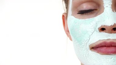 Yüzünde beyaz yeşil çamur maskesi olan genç bir kadın. Genç kız yağlı cildiyle ilgileniyor, gözenekleri temizliyor. Güzellik tedavisi. Cilt bakımı.