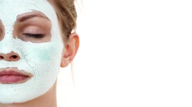 Yüzünde beyaz yeşil çamur maskesi olan genç bir kadın. Genç kız yağlı cildiyle ilgileniyor, gözenekleri temizliyor. Güzellik tedavisi. Cilt bakımı.