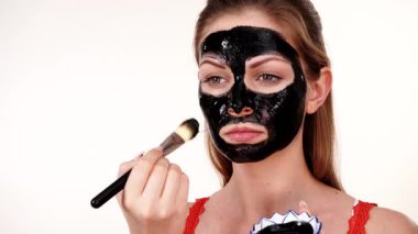 Genç bir kadın yüzüne karbonhidrat temizleme maskesi takıyor, yüzüne, beyaza. Genç kız yağlı cildiyle ilgileniyor, gözenekleri temizliyor. Güzellik tedavisi. Cilt bakımı.