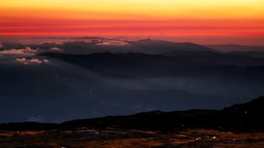 Rüzgar türbinleri gün batımında bulutların üzerinde. Portekiz 'deki Torre Dağı tepesinden Serra da Estrela' nın görüntüsü.