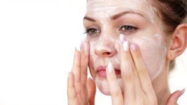 Maske takan genç bir kadın yüzüne nemlendirici krem sürüyor. Cilt nemlendiricisine dikkat eden bir kız. Cilt bakımı.
