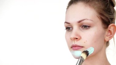 Yüzüne yeşil çamur maskesi dayayan genç bir kadın. Genç kız yağlı cildiyle ilgileniyor, gözenekleri temizliyor. Güzellik tedavisi. Cilt bakımı.