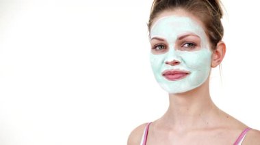 Yüzünde beyaz yeşil çamur maskesi olan genç bir kadın. Genç kız yağlı cildiyle ilgileniyor, gözenekleri temizliyor. Güzellik tedavisi. Cilt bakımı.