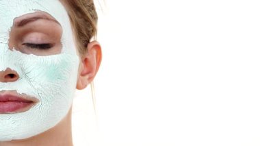 Yüzünde beyaz yeşil çamur maskesi olan genç bir kadın. Genç kız yağlı cildiyle ilgileniyor, gözenekleri temizliyor. Güzellik tedavisi. Cilt bakımı.