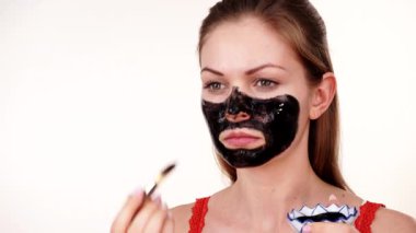 Genç bir kadın yüzüne karbonhidrat temizleme maskesi takıyor, yüzüne, beyaza. Genç kız yağlı cildiyle ilgileniyor, gözenekleri temizliyor. Güzellik tedavisi. Cilt bakımı.