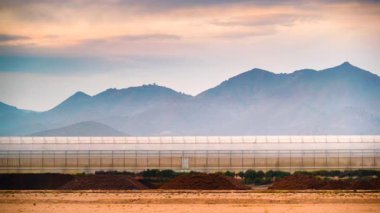Akşamları, ticari seralarla birlikte kıyı manzarası üzerinde hareket eden bulutların hızlanması. Endüstriyel tarım. Murcia bölgesi, İspanya.