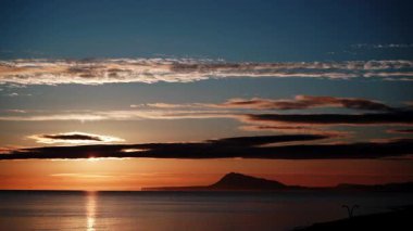 Sabahın erken saatlerinde denizde hareket eden bulutların hızlanması, güneşin doğması. Doğa manzarası. Gandia Sahili, Valencia İspanya.