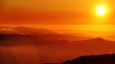Bulutların üstündeki yüksek dağlarda yanan günbatımı. Portekiz 'de Serra da Estrela.
