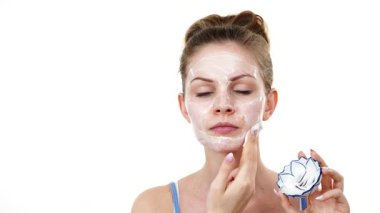 Maske takan genç bir kadın yüzüne nemlendirici krem sürüyor. Cilt nemlendiricisine dikkat eden bir kız. Cilt bakımı.