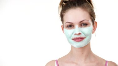 Yüzünde beyaz yeşil çamur maskesi olan genç bir kadın. Genç kız yağlı cildiyle ilgileniyor, gözenekleri temizliyor. Güzellik tedavisi. Cilt bakımı.