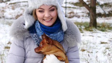 Genç bir kadın kış havasında yavru köpeğiyle dışarıda oynuyor..