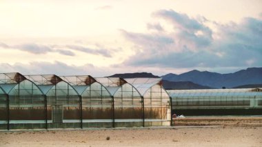 Akşamları, ticari seralarla birlikte kıyı manzarası üzerinde hareket eden bulutların hızlanması. Endüstriyel tarım. Murcia bölgesi, İspanya.
