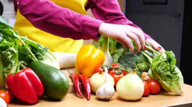 Mutfak masasında ağır çekimde diyet yapmak için sağlıklı sebzeler gösteren tanınmamış kadın elleri..