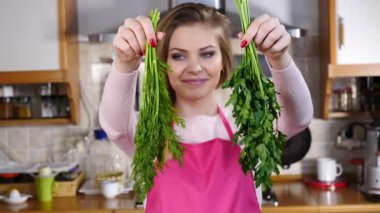 Yeşil dereotu ve maydanozlu sebze çeşnisi tutan genç ve güzel bir kadın. Sağlıklı gıda kokusu kavramı.