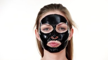 Yüzünde karbonhidratlı siyah kabuk soyma maskesi olan genç bir kadın. Kozmetik, beyazın üzerinde çıkarmaya hazır. Yağlı ciltle ilgilenen genç bir kız. Güzellik tedavisi. Cilt bakımı.