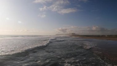 Kumsal kıyısı. Deniz dalgaları yavaş çekimde sıçrıyor.