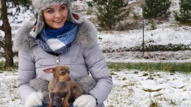 Genç bir kadın köpeğiyle oynuyor, pinscher ratter prazsky krysarik, kış havasında açık havada..