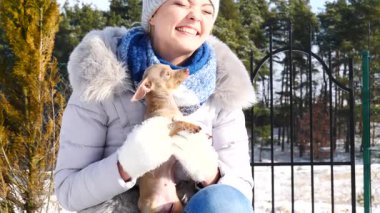 Genç bir kadın köpeğiyle oynuyor, pinscher ratter prazsky krysarik, kış havasında açık havada..