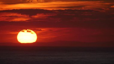 Deniz üzerinde gün batımında kızıl gökyüzü. Güneş ufukta batıyor. Akşam doğa manzarası.