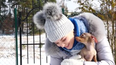 Genç bir kadın köpeğiyle oynuyor, pinscher ratter prazsky krysarik, kış havasında açık havada..