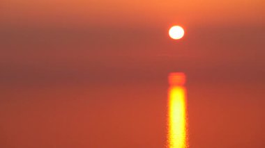 Deniz suyunun üzerinde turuncu kırmızı gün batımı. Akşam doğa manzarası.