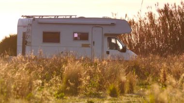 Kamp aracı, İspanya 'nın güneşli bir gününde sahildeki çayır arazisinde kamp yapıyor. Karavanla seyahat ediyorum. Karavan tatili.