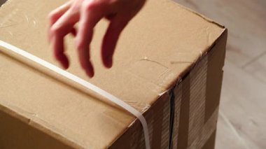 Boks yapıyorum. Kahverengi karton kutu, kargo paketi, kesici bıçakla bant kesme. Teslimat konsepti.