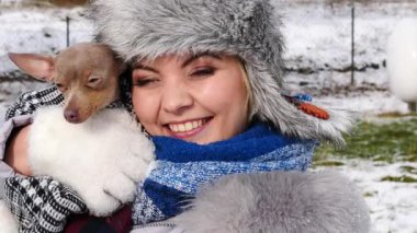 Köpeğiyle oynayan genç bir kadın, pinscher ratter prazsky krysarik, kış havasında dışarıda. Dişi köpek yavrusuna sevgiyle sarılıyor..