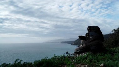 Akdeniz 'de, kayalık deniz kıyısında uzanan yürüyüş ayakkabılarıyla hareket eden bulutların hızlanması. Deniz kenarındaki patikada yürüyüş. Seyahat, macera konsepti.