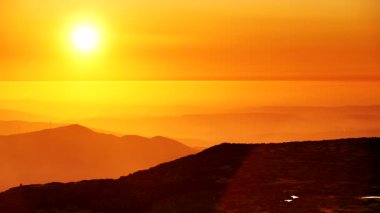 Bulutların üstündeki yüksek dağlarda yanan günbatımı. Portekiz 'de Serra da Estrela.
