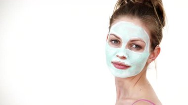 Yüzünde beyaz yeşil çamur maskesi olan genç bir kadın. Genç kız yağlı cildiyle ilgileniyor, gözenekleri temizliyor. Güzellik tedavisi. Cilt bakımı.