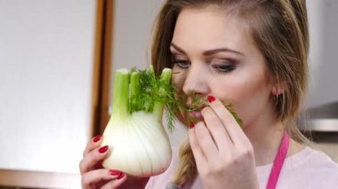 Çiğ sebze rezenesi tutan ve kokusunu alan mutlu genç bir kadın. Doğal organik sağlıklı gıda konsepti.