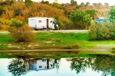 Doğada kamp yapmak. Göl kıyısındaki kamp aracı suya yansıyor. Povoa e Meadas Barajı, Castelo de Vide, Alentejo Portekiz. Karavanla git..