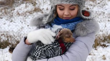 Köpeğiyle oynayan genç bir kadın, pinscher ratter prazsky krysarik, kış havasında dışarıda. Dişi köpek yavrusuna sevgiyle sarılıyor..