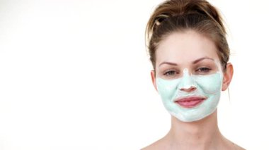 Yüzünde beyaz yeşil çamur maskesi olan genç bir kadın. Genç kız yağlı cildiyle ilgileniyor, gözenekleri temizliyor. Güzellik tedavisi. Cilt bakımı.