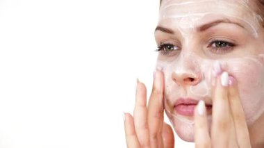 Maske takan genç bir kadın yüzüne nemlendirici krem sürüyor. Cilt nemlendiricisine dikkat eden bir kız. Cilt bakımı.