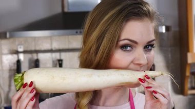 Beyaz turp kökü tutan ve onu koklayan genç ve güzel bir kadın. Sağlıklı gıda konsepti.