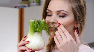 Çiğ sebze rezenesi tutan ve kokusunu alan mutlu genç bir kadın. Doğal organik sağlıklı gıda konsepti.