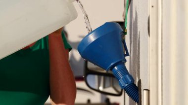 Karavan su deposunu huni kullanarak dolduran bir kadına yaklaş. Karavanla seyahat ediyorum. Karavan tatili.