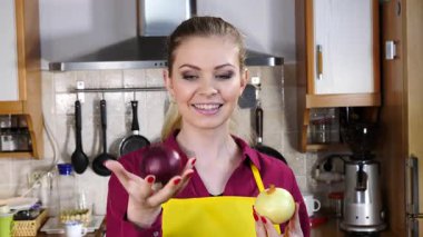 Kırmızı ve beyaz soğan tutan mutlu kadın yavaş çekimde aralarında seçim yapıyor. Sağlıklı beslenme, gıda kararları kavramı.