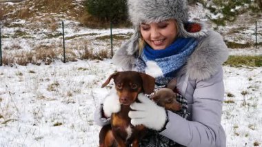 Genç kadın köpekleriyle oynuyor, pinscher ratter prazsky krysarik ve dachshund, kış havasında açık havada..