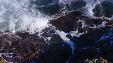 Büyük dalgalar kayalıklara çarpıyor. Ağır çekim. Yukarıdan görüntüle