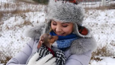 Köpeğiyle oynayan genç bir kadın, pinscher ratter prazsky krysarik, kış havasında dışarıda. Dişi köpek yavrusuna sevgiyle sarılıyor..