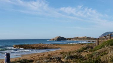 Sahil manzarası, deniz suyuna giden ahşap yolu olan kayalık deniz kıyısı. Cala Magre Sahili, Calique Bölgesel Parkı, Murcia Bölgesi İspanya.