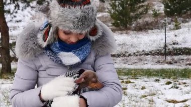 Genç bir kadın köpeğiyle oynuyor, pinscher ratter prazsky krysarik, kış havasında açık havada..