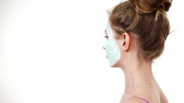 Yüzünde beyaz yeşil çamur maskesi olan genç bir kadın. Genç kız yağlı cildiyle ilgileniyor, gözenekleri temizliyor. Güzellik tedavisi. Cilt bakımı.