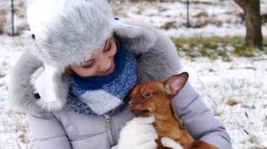 Genç bir kadın kış havasında yavru köpeğiyle dışarıda oynuyor..