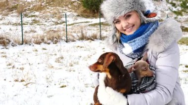 Genç kadın köpekleriyle oynuyor, pinscher ratter prazsky krysarik ve dachshund, kış havasında açık havada..