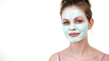 Yüzüne yeşil çamur maskesi dayayan genç bir kadın. Genç kız yağlı cildiyle ilgileniyor, gözenekleri temizliyor. Güzellik tedavisi. Cilt bakımı.