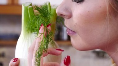 Çiğ sebze rezenesi tutan ve kokusunu alan mutlu genç bir kadın. Doğal organik sağlıklı gıda konsepti.